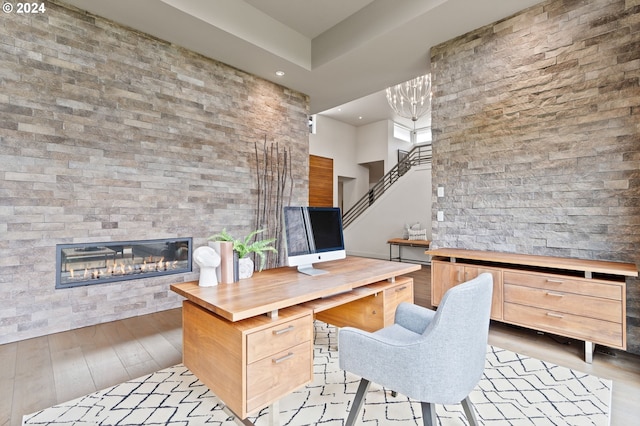 office with a glass covered fireplace, light wood-style flooring, recessed lighting, and a chandelier