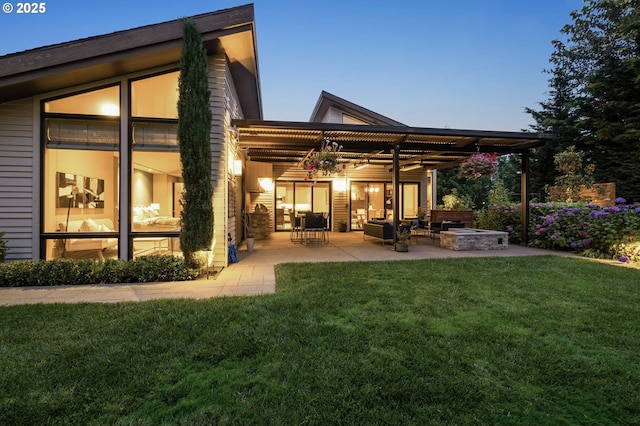 back house at dusk featuring a patio, a lawn, and a fire pit