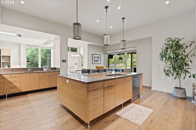 kitchen featuring dishwasher, a sink, modern cabinets, light brown cabinets, and recessed lighting