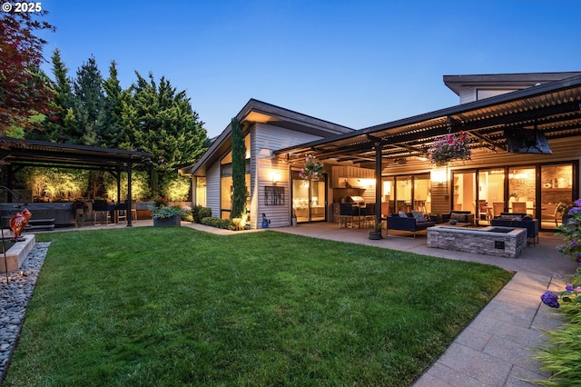 back house at dusk featuring a lawn, an outdoor living space with a fire pit, and a patio area