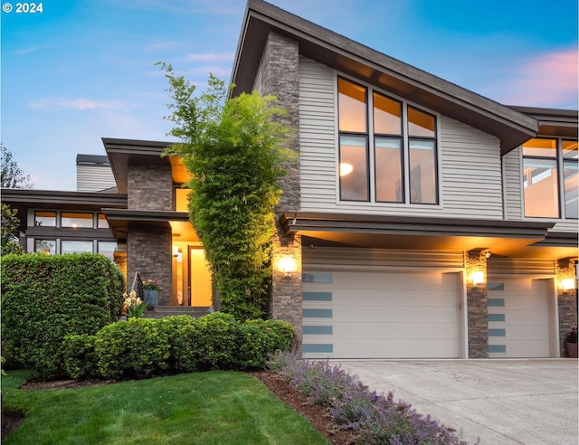 view of front of property featuring an attached garage, stone siding, concrete driveway, and a front lawn