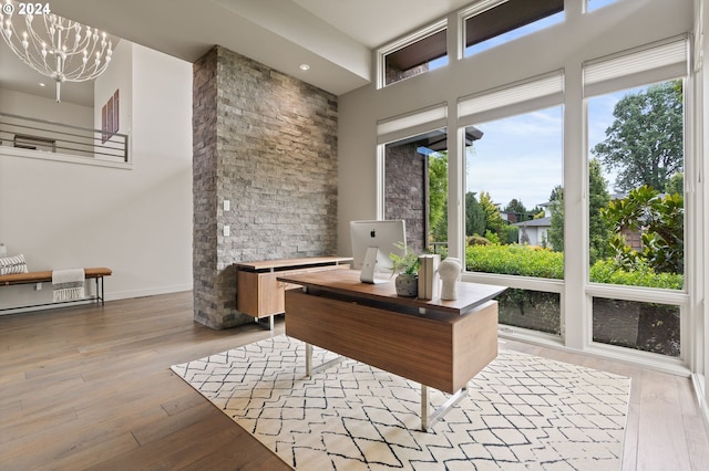 home office featuring hardwood / wood-style floors, a chandelier, a towering ceiling, and baseboards