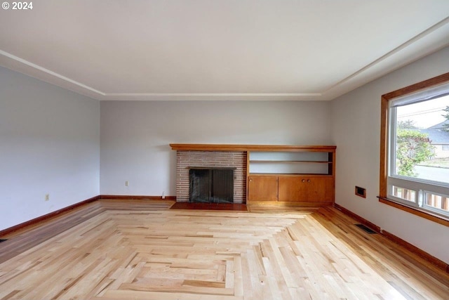 unfurnished living room with light parquet floors and a brick fireplace