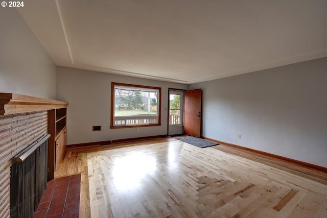 unfurnished living room featuring a brick fireplace and hardwood / wood-style flooring