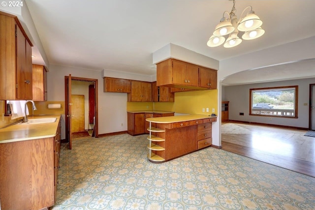 kitchen with decorative light fixtures, light hardwood / wood-style floors, sink, and a chandelier