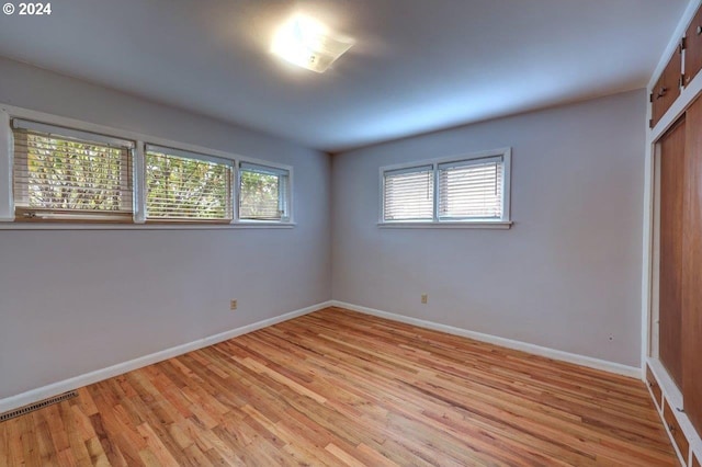 unfurnished bedroom featuring a closet, light wood-type flooring, and multiple windows