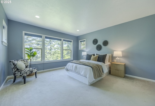 bedroom with baseboards, visible vents, and light colored carpet