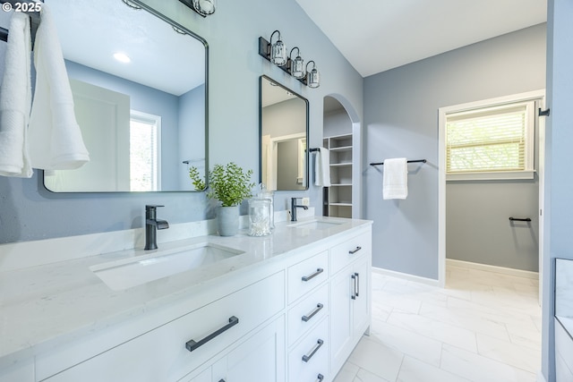 full bathroom featuring a healthy amount of sunlight, a sink, and marble finish floor