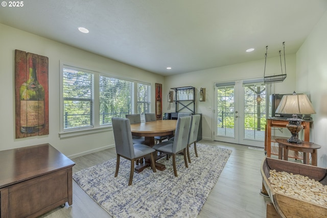 dining area with baseboards, a wealth of natural light, french doors, and light wood-style flooring