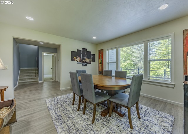 dining space featuring stairway, baseboards, plenty of natural light, and light wood-style floors
