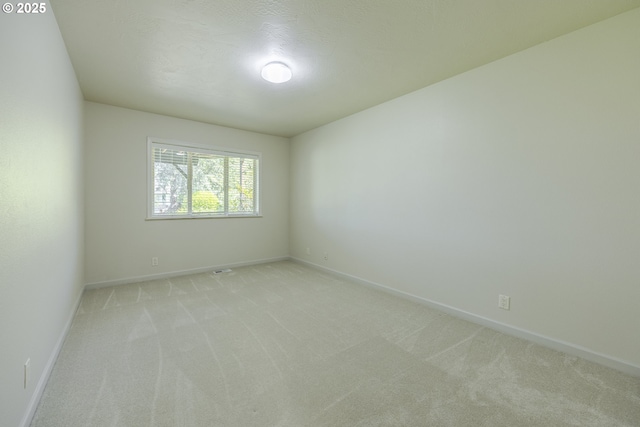 unfurnished room with baseboards and light carpet