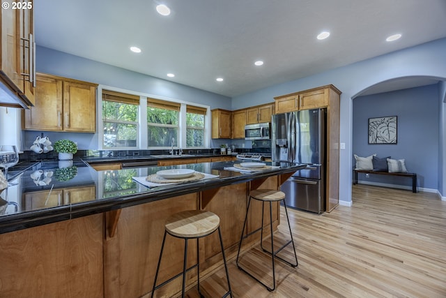 kitchen with appliances with stainless steel finishes, arched walkways, a sink, a peninsula, and recessed lighting