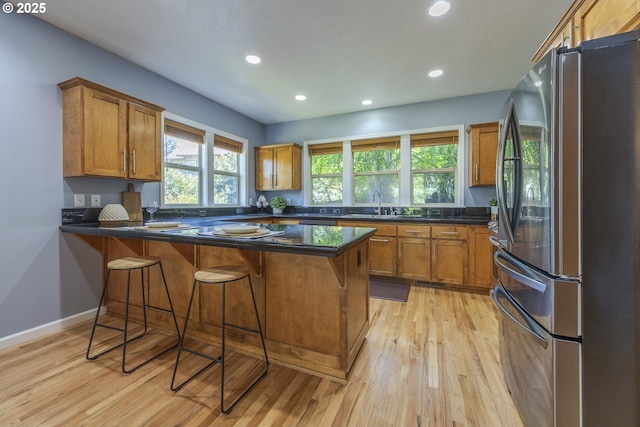 kitchen with recessed lighting, freestanding refrigerator, a peninsula, and brown cabinetry