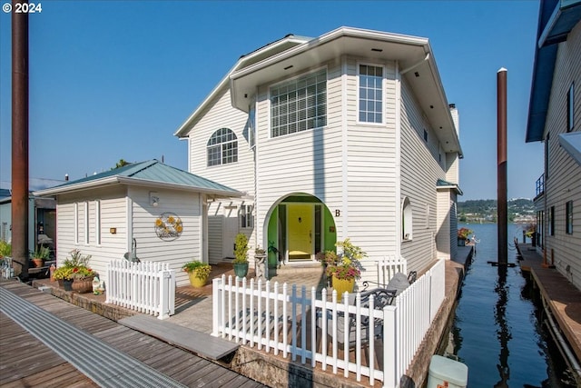 view of front of home with fence, a water view, and metal roof