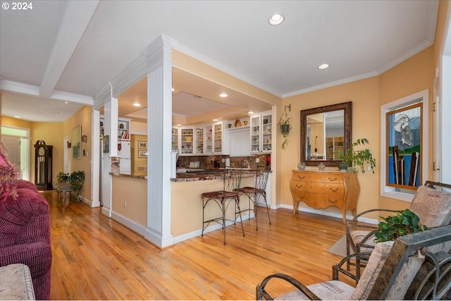 interior space featuring crown molding, light wood-type flooring, white cabinets, and decorative backsplash