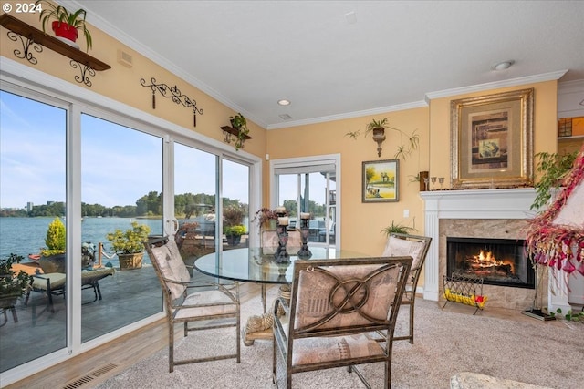 interior space with crown molding, hardwood / wood-style flooring, a water view, and a fireplace