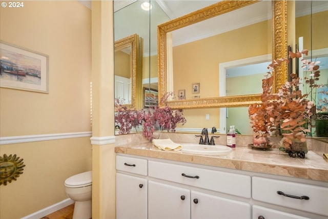 bathroom with vanity, toilet, ornamental molding, and hardwood / wood-style flooring