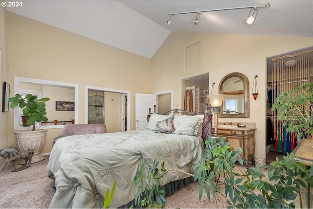 carpeted bedroom with track lighting and high vaulted ceiling