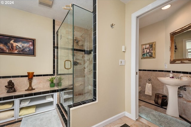 bathroom featuring tile walls, a textured ceiling, and a shower with shower door