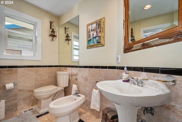 bathroom featuring a bidet, toilet, tile walls, and decorative backsplash