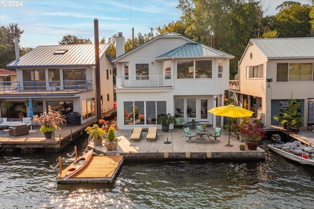 rear view of property with a balcony, an outdoor hangout area, a water view, and a patio