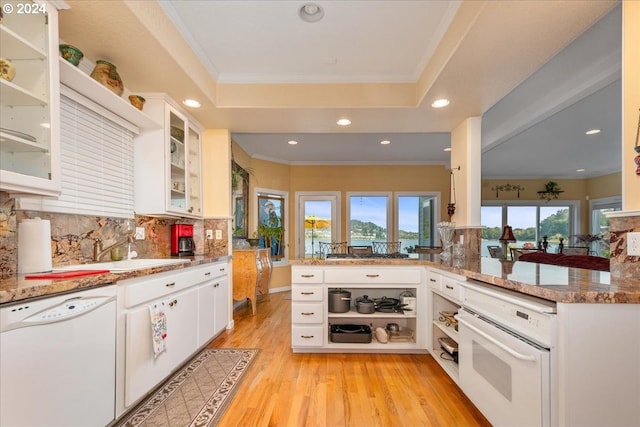 kitchen with light stone countertops, white appliances, white cabinetry, and kitchen peninsula