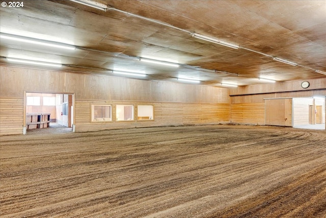 carpeted spare room with wood walls