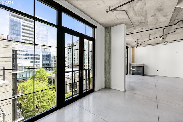 doorway to outside featuring a glass covered fireplace, plenty of natural light, a view of city, and finished concrete floors