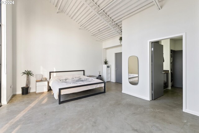 bedroom featuring concrete floors and high vaulted ceiling