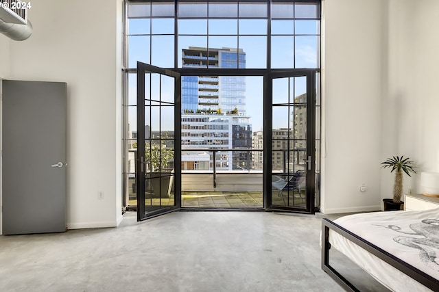 unfurnished bedroom featuring a city view, access to outside, multiple windows, and concrete flooring