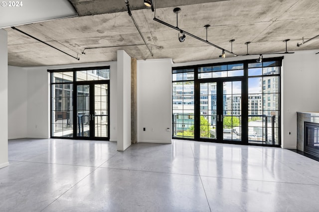 interior space featuring french doors, baseboards, a glass covered fireplace, and expansive windows