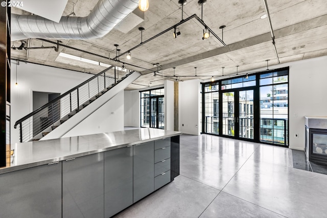 kitchen with finished concrete flooring, stainless steel countertops, open floor plan, gray cabinets, and modern cabinets