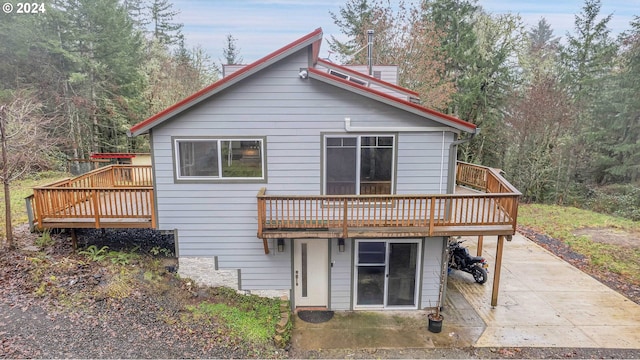 back of house featuring a wooden deck and a patio