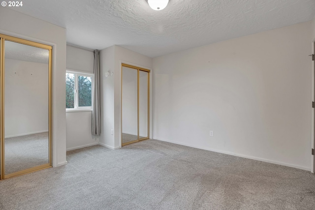 unfurnished bedroom featuring light colored carpet, a textured ceiling, and a closet