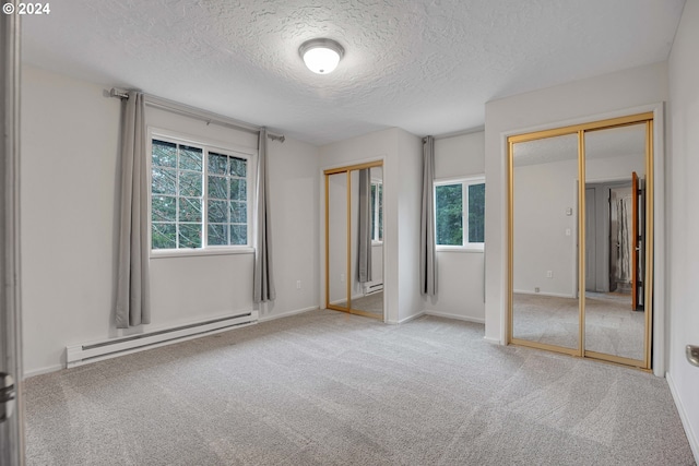 22715 SW Eagle Point Rd, Sheridan, OR 97378 - unfurnished bedroom with baseboard heating, two closets, a textured ceiling, carpet, and a baseboard heating unit