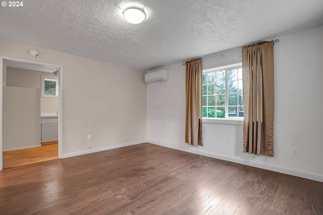 empty room with hardwood / wood-style floors, a textured ceiling, and a wall mounted AC