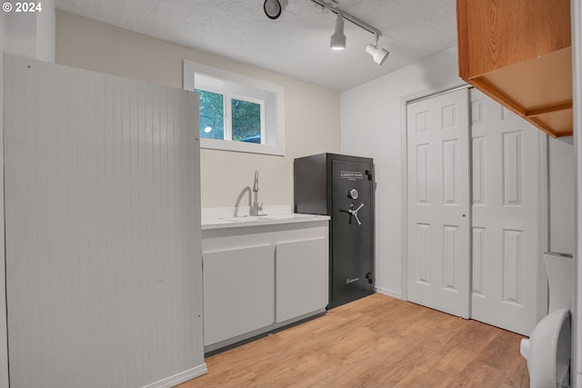 laundry area featuring sink, light hardwood / wood-style floors, and a textured ceiling