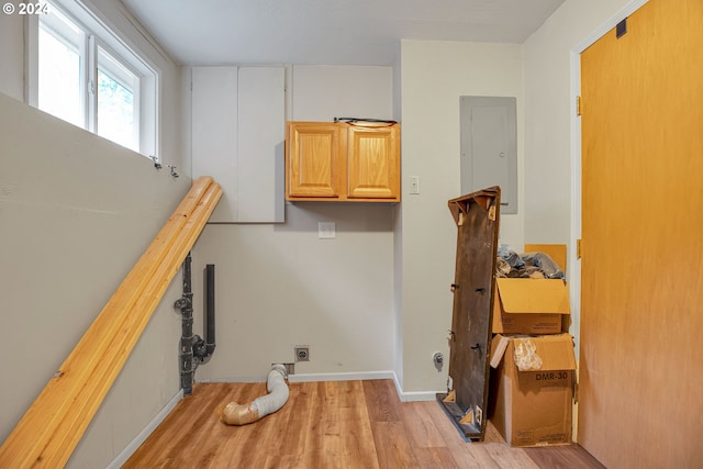 washroom with electric dryer hookup, electric panel, cabinets, and light hardwood / wood-style floors