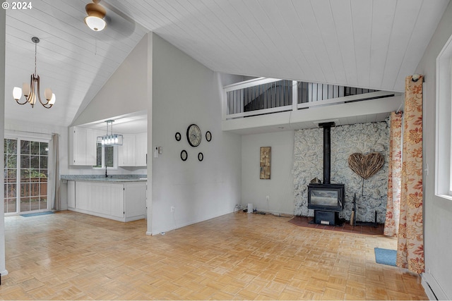 unfurnished living room with wood ceiling, ceiling fan with notable chandelier, high vaulted ceiling, light parquet flooring, and a wood stove