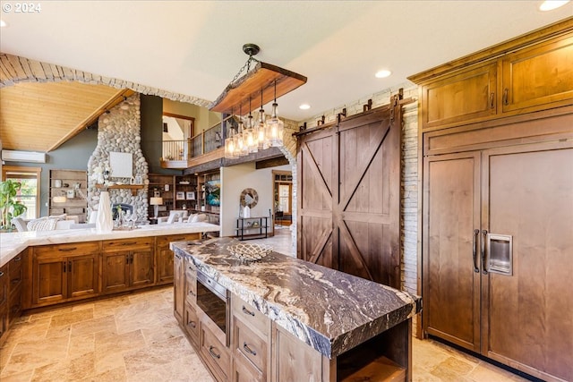33138 SE Bluff Rd, Boring, OR 97009 - kitchen featuring paneled fridge, light stone finish floors, a barn door, recessed lighting, and brown cabinets