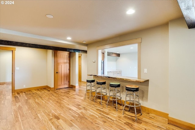 kitchen featuring light hardwood / wood-style floors, kitchen peninsula, and a breakfast bar area