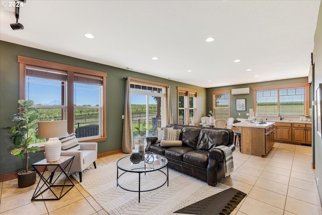 living room with a healthy amount of sunlight, light tile patterned floors, and an AC wall unit