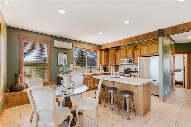 kitchen featuring a center island, light tile patterned floors, appliances with stainless steel finishes, and a wall mounted AC