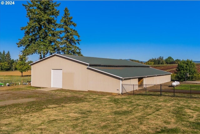 view of side of property featuring an outbuilding, a rural view, and a lawn