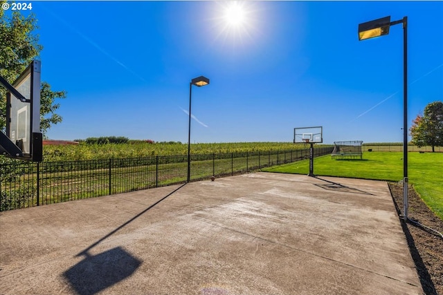 view of sport court with a lawn and a rural view