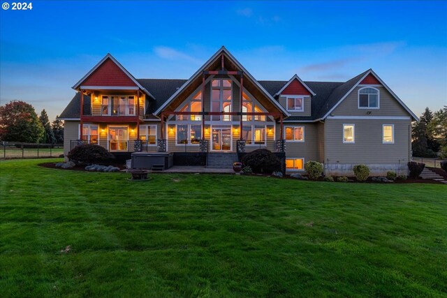 back house at dusk with a patio, a yard, a balcony, and a hot tub