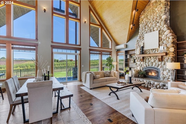 living room with a high ceiling, a stone fireplace, a wall unit AC, wood ceiling, and hardwood / wood-style flooring