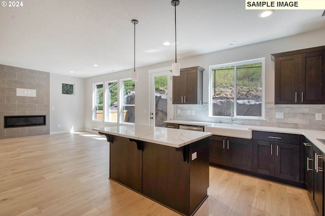 kitchen featuring light stone countertops, light hardwood / wood-style flooring, a breakfast bar area, and sink