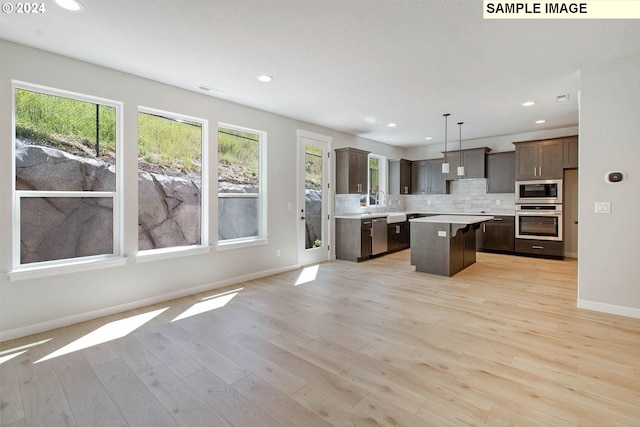 kitchen with dark brown cabinetry, a center island, hanging light fixtures, light hardwood / wood-style floors, and appliances with stainless steel finishes