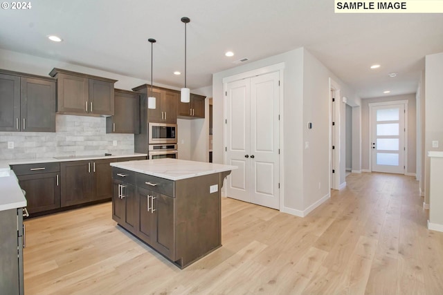 kitchen featuring dark brown cabinetry, a center island, hanging light fixtures, light hardwood / wood-style flooring, and appliances with stainless steel finishes